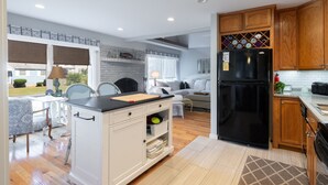 A modern kitchen with wooden cabinets, a black refrigerator, and a dining area with a table and chairs.