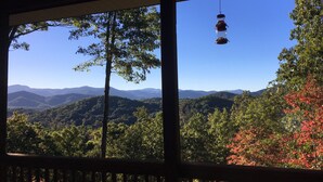 A view from a window with a hanging bird feeder, a wooden railing, and a forested landscape with mountains in the distance. - Red Rooster Retreat,Hot Tub+game area+firepit & LRG deck w/amazing Mountain View (Franklin)