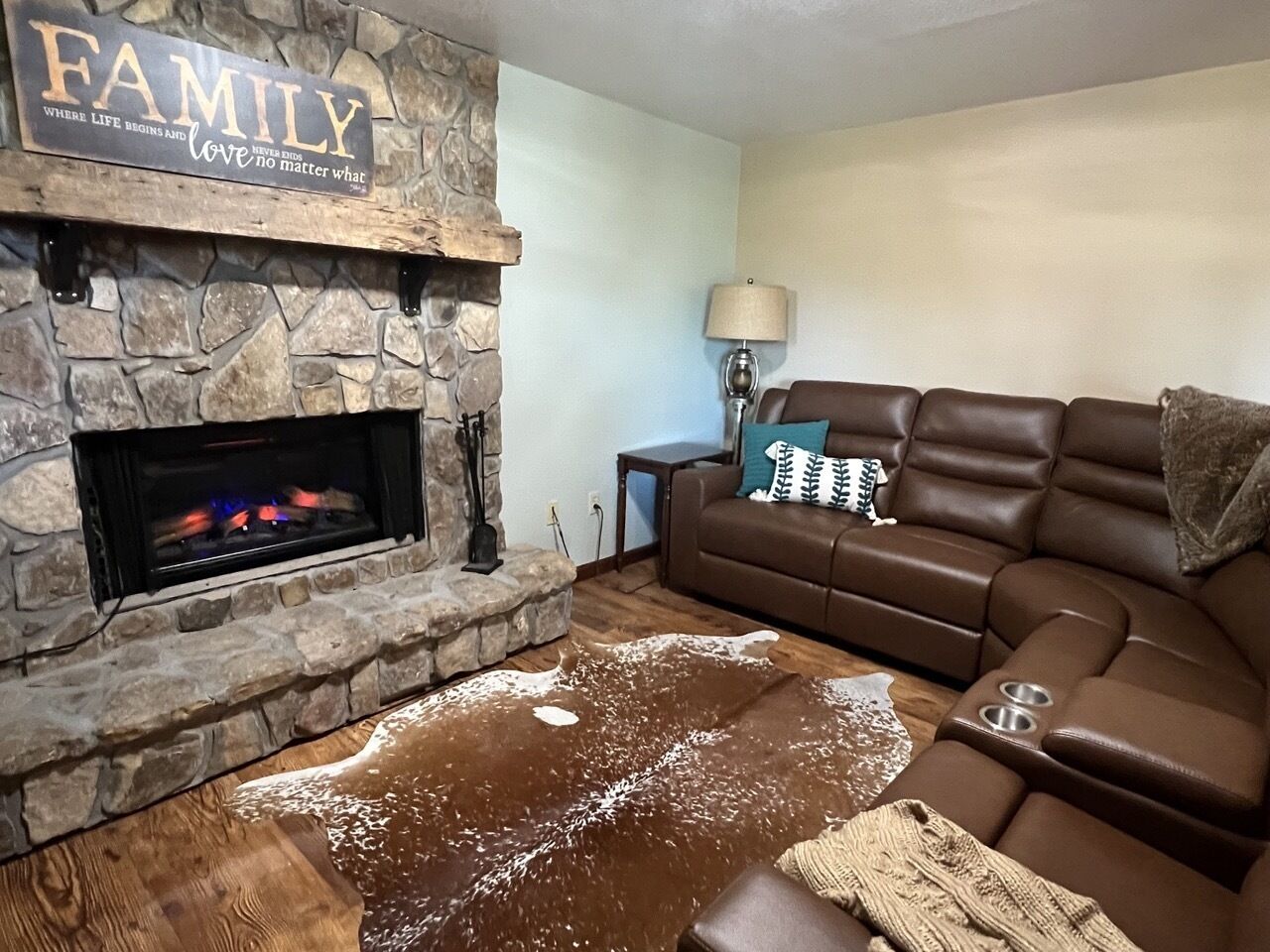 Una sala de estar acogedora con chimenea de piedra, sofá de cuero y alfombra.