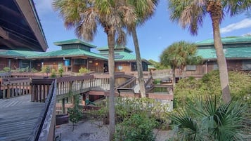 Ein Resort mit mehreren Terrassen aus Holz, Palmen und einem Gebäude mit Gründach.