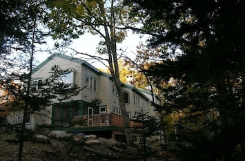 Quiet wooded area in back, sunny lawn out front. Note screened in porch & deck.
