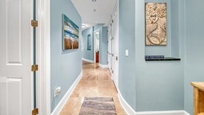 Un pasillo con paredes azul claro, un tapete estampado y una obra de arte enmarcada a la derecha.