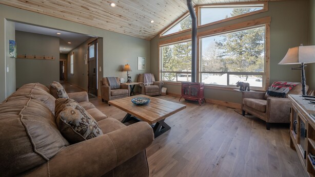 Una sala de estar acogedora con techo de madera, ventanas amplias, chimenea y asientos confortables.