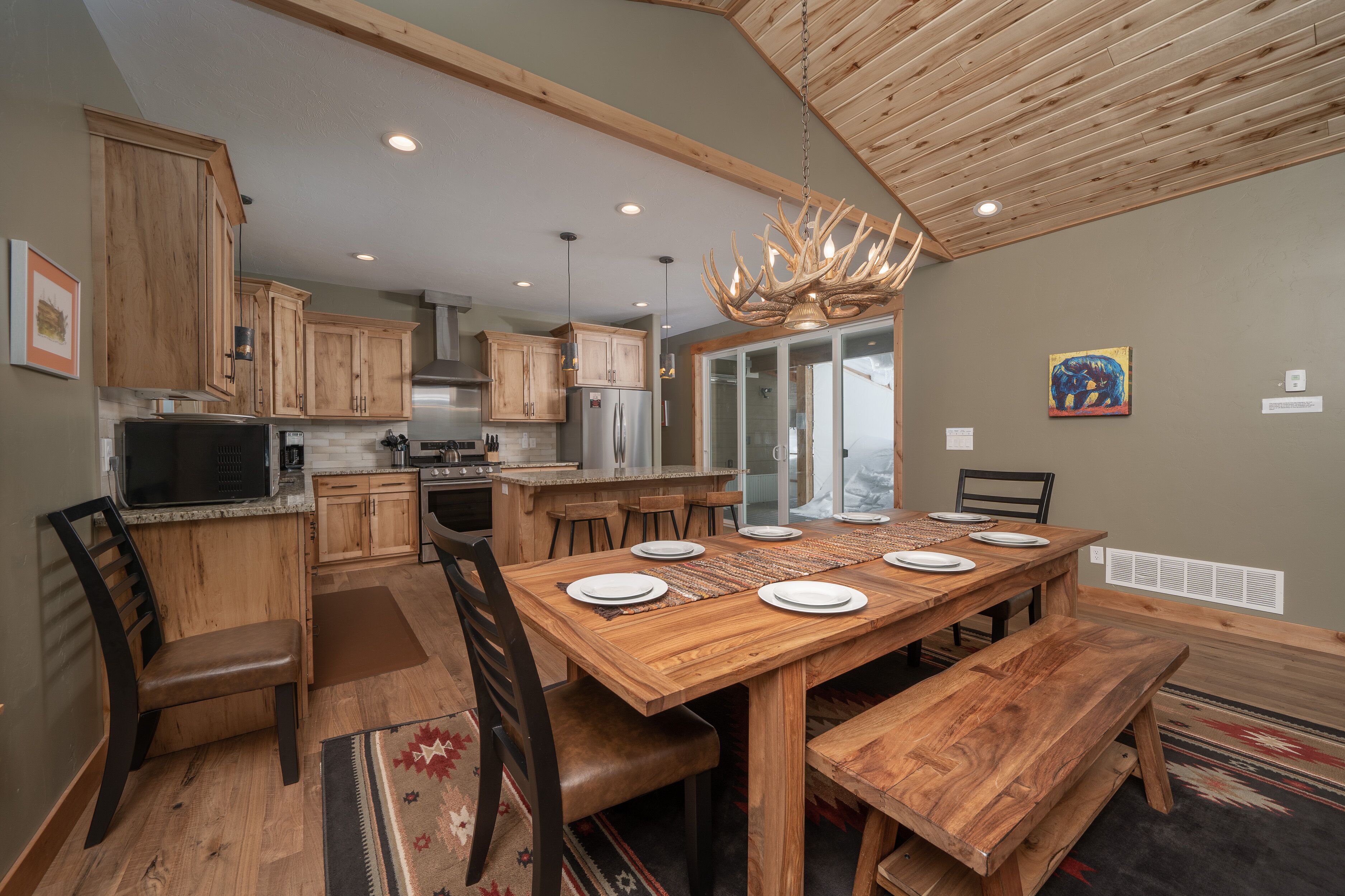 A spacious kitchen with wooden cabinets, a large dining table, and a chandelier.