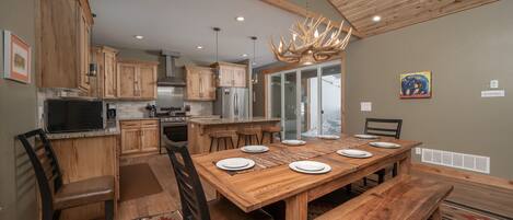 A spacious kitchen with wooden cabinets, a large dining table, and a chandelier.