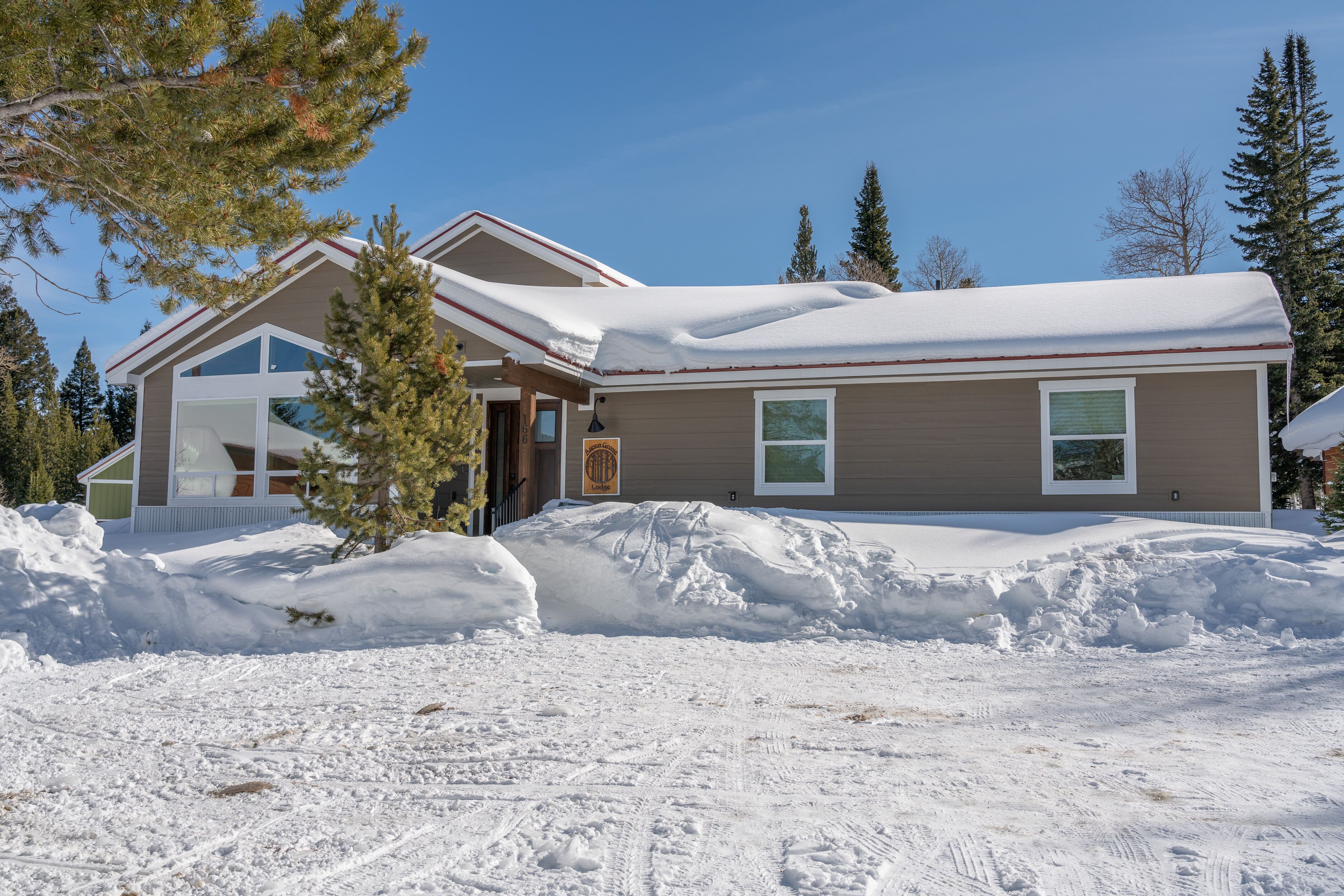 A two-story house with a snow-covered roof and a large driveway.