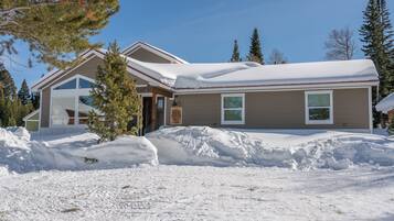 A two-story house with a snow-covered roof and a large driveway.