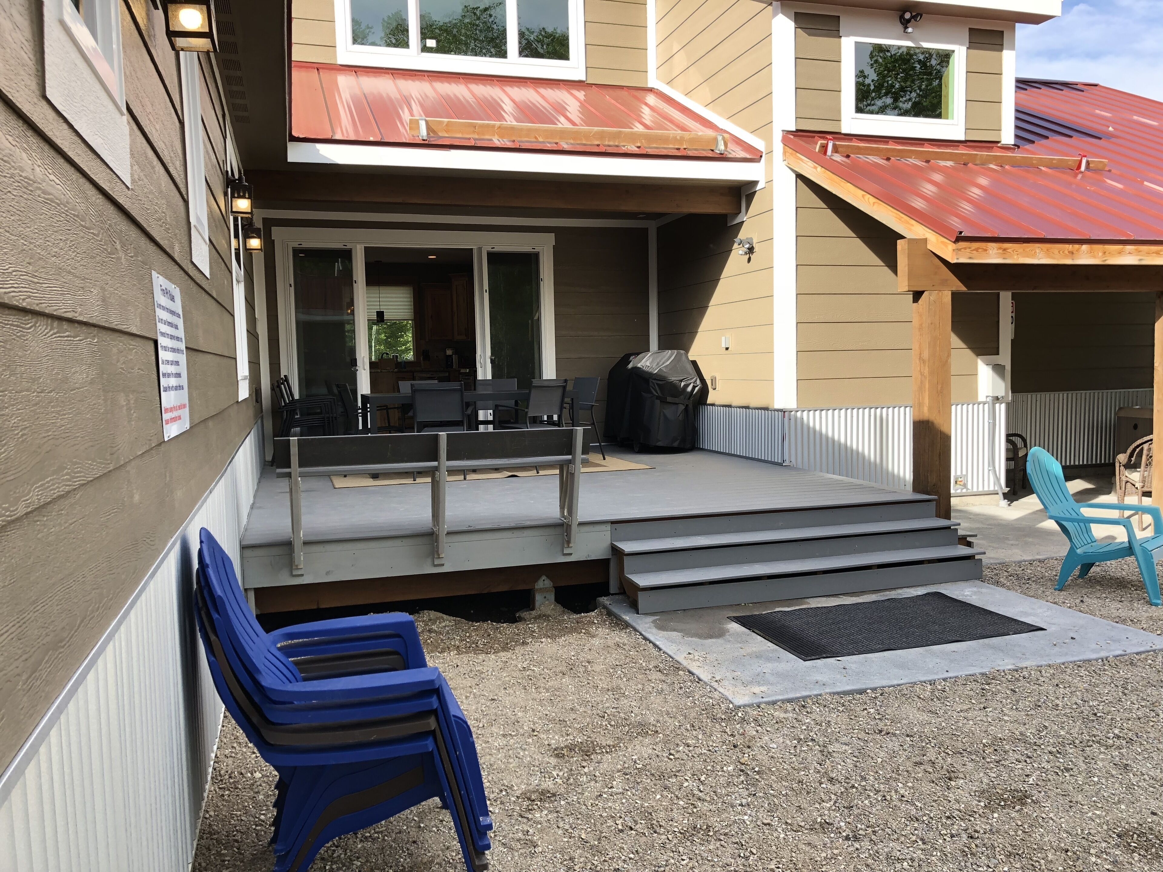 A covered outdoor area with a patio, steps leading up to a deck, and a grill.