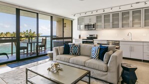 A modern living room with a sofa, coffee table, and a view of the ocean. - Live On the Ocean and Sleep to Surf Sounds in Idyllic Poipu. Trade Winds & AC.
 (Poipu)