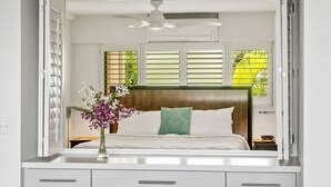 A bedroom with a bed, a nightstand, a vase with flowers, and a ceiling fan. - Live On the Ocean and Sleep to Surf Sounds in Idyllic Poipu. Trade Winds & AC.
 (Poipu)