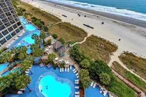 Un complexe hôtelier doté de plusieurs piscines, d’une plage et d’un immeuble de grande hauteur.