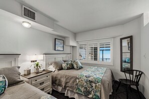 Un dormitorio con cama, mesita de noche, lámpara, silla, ventana y espejo.