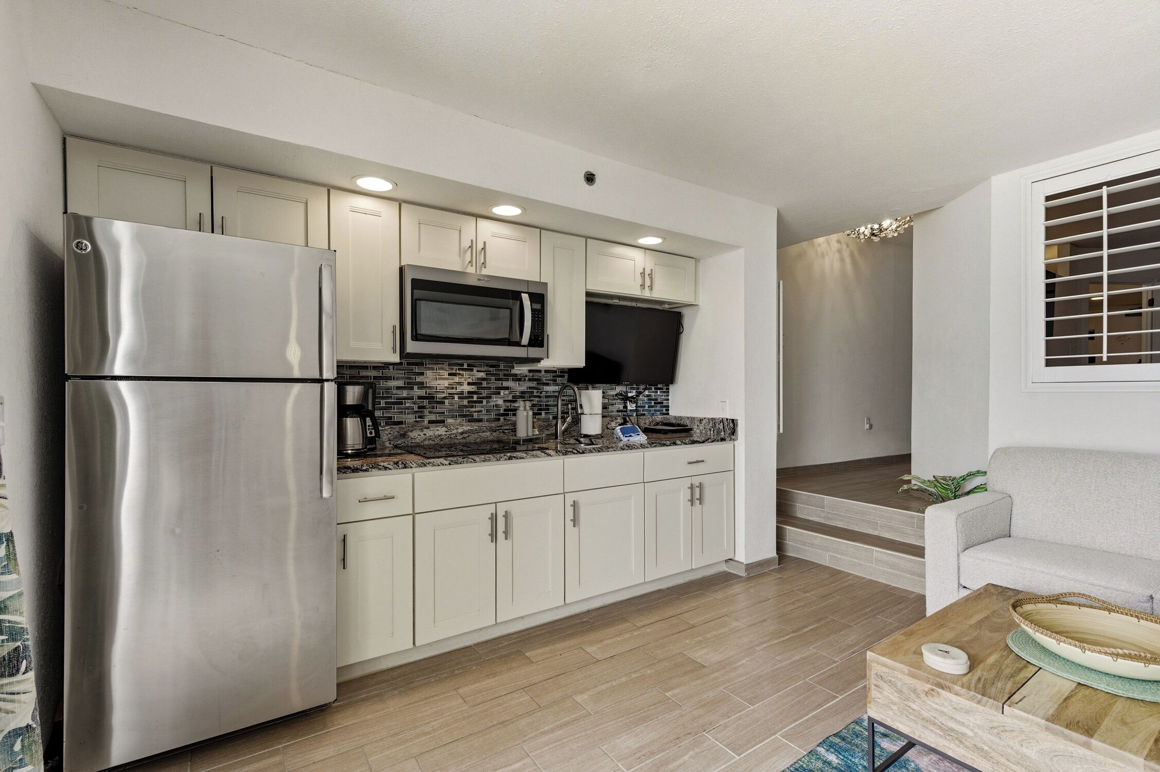 A modern kitchen with stainless steel appliances, white cabinets, and a tiled backsplash.