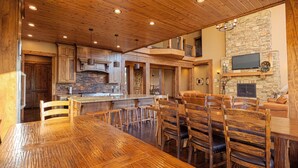 A spacious kitchen with wooden cabinets, a large island, and a stone fireplace. - Spring Shores Lodge - Luxury mountain estate on a private lake. With 3 en-suite king bedrooms 4 other bedrooms and 2 large bunkrooms, it sleeps up to 40 guests—perfect for family reunions, retreats, and group getaways in a secluded luxury setting. (Ashton)