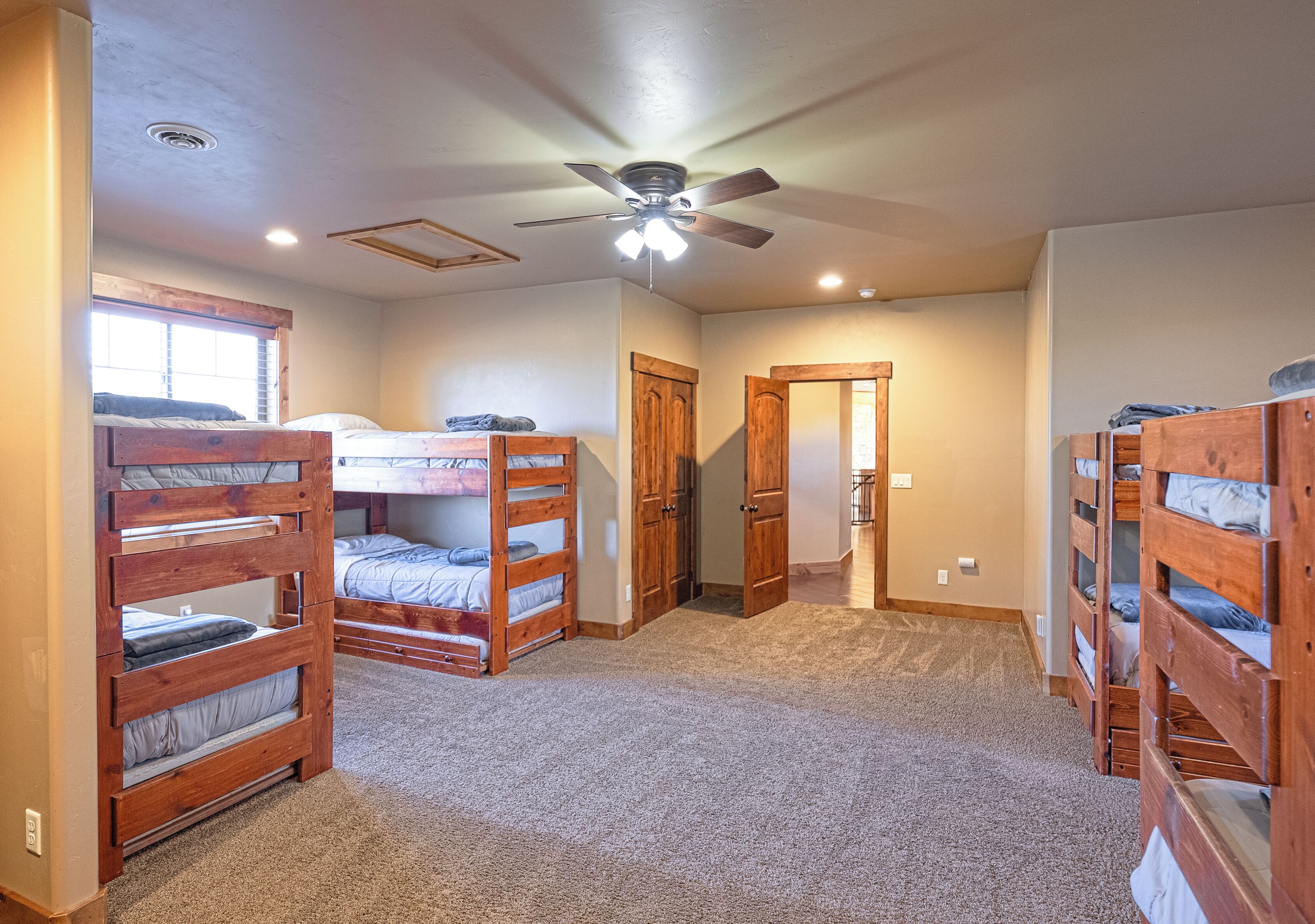 A bedroom with bunk beds, a ceiling fan, and a carpeted floor.