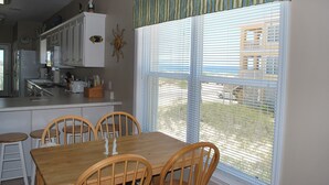 A kitchen with white cabinets, a wooden dining table, and a window with blinds. - Oh the views, hear the surf Great location all year long (Gulf Shores)