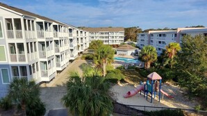 A multi-story hotel with balconies, a playground, and a swimming pool. - Family Favorite on Shore Drive ~ Ocean View ~ 2 Pools ~ Sleeps 8 (Myrtle Beach)