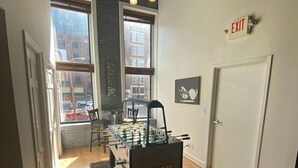 Une pièce avec un baby-foot marqué du nom « TORNADO », de grandes fenêtres, un panneau de sortie et un lustre.