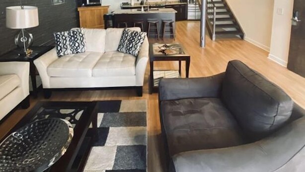 Un salon moderne comprenant un canapé, une table basse et un coin repas avec un escalier menant à une mezzanine.