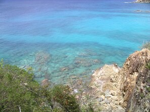 Un paisaje costero con aguas turquesas cristalinas, acantilados rocosos y abundante vegetación.