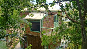 Eine Holzhütte mit Balkon, umgeben von üppiger Vegetation.