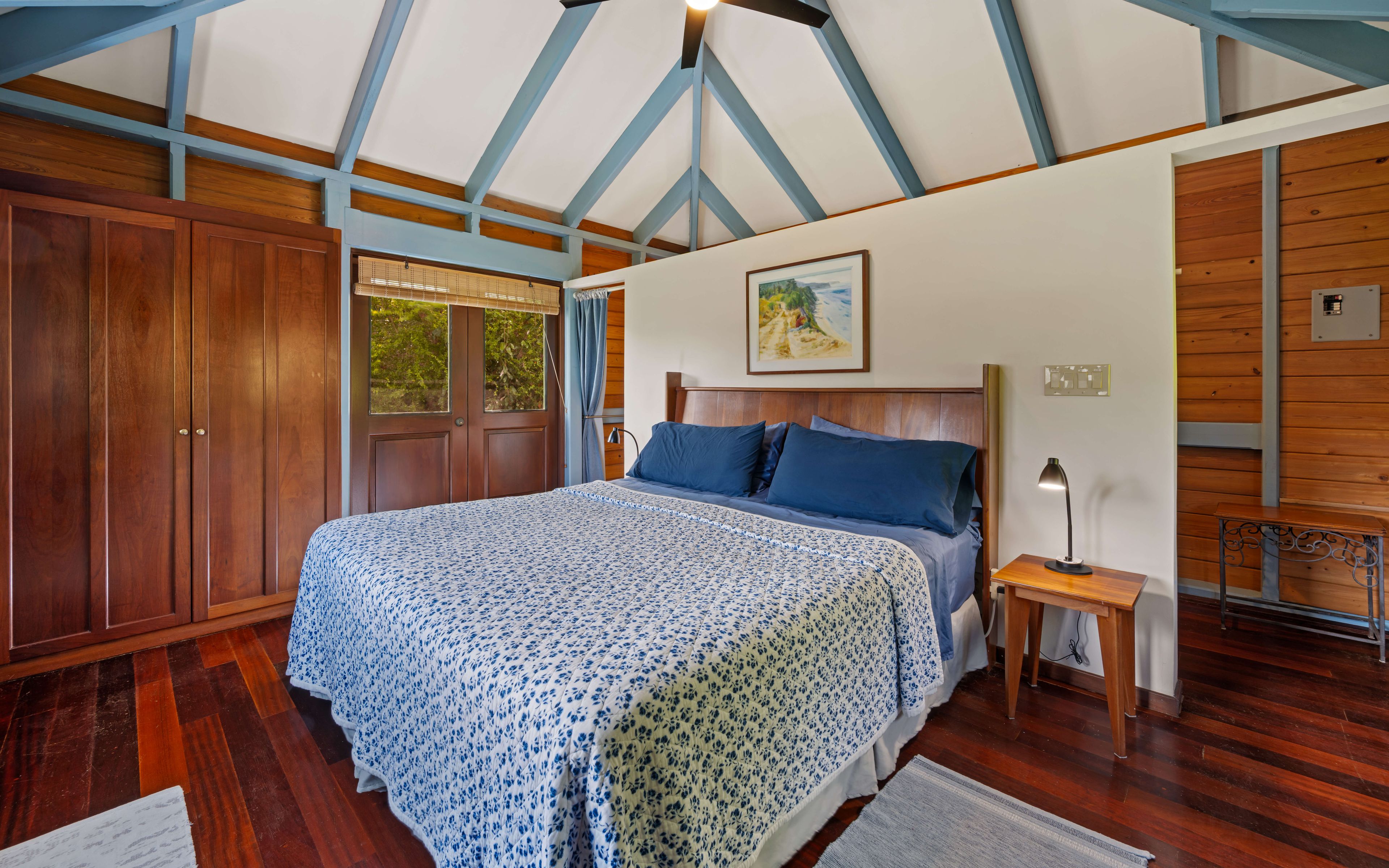 Une chambre avec un grand lit, une armoire en bois et un tableau accroché au mur.