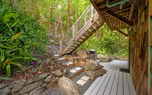Une terrasse en bois avec un chemin de pierre menant à un escalier en bois.