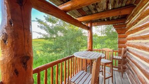 Eine Holzterrasse mit Tisch und Stühlen, mit Blick auf eine grüne Landschaft.
