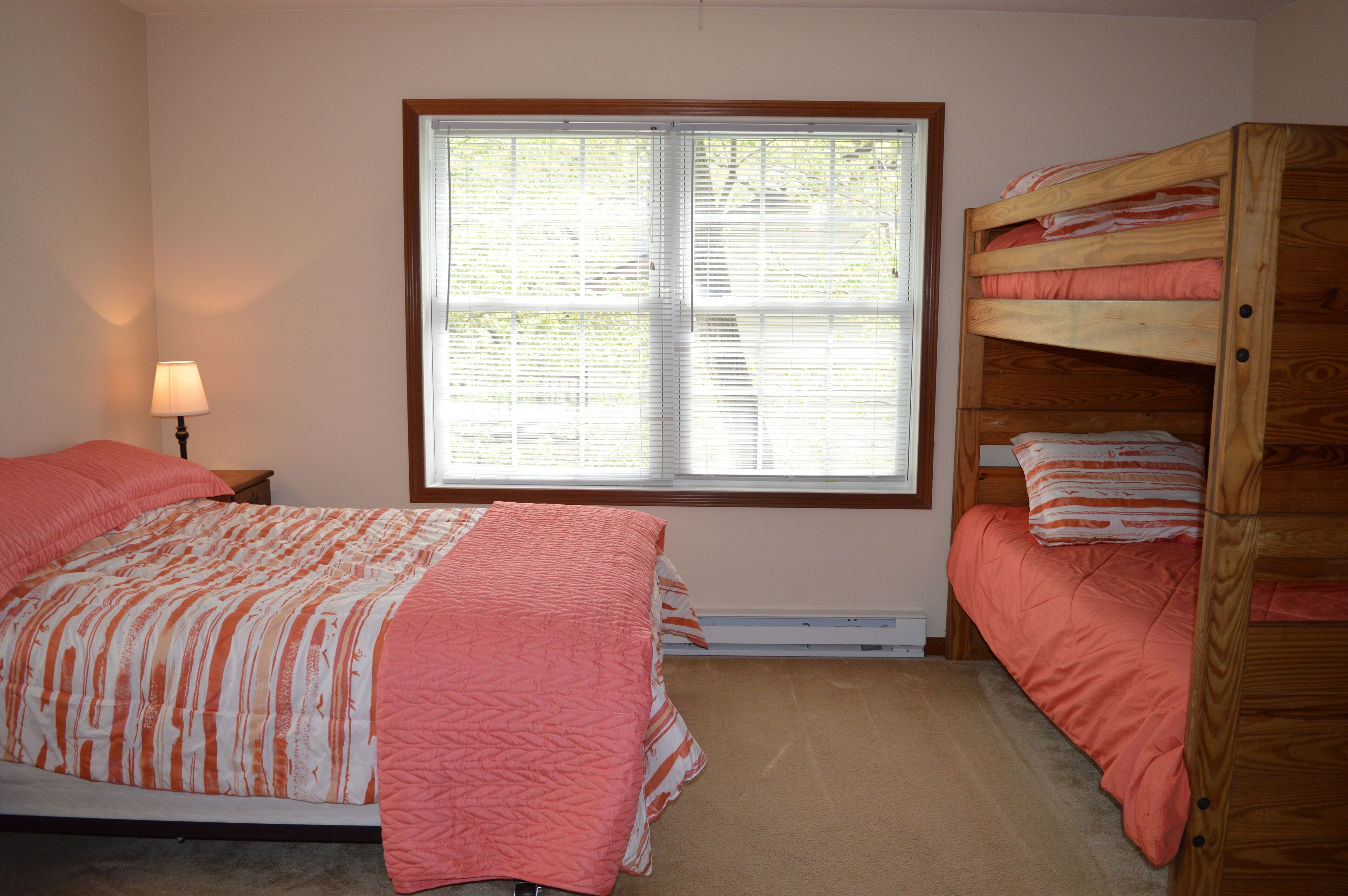 A bedroom with a bunk bed, a single bed, and a window with blinds.