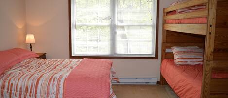 A bedroom with a bunk bed, a single bed, and a window with blinds.