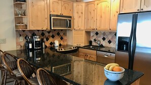 A kitchen with wooden cabinets, a microwave, a stove, a refrigerator, and a bowl of fruit on the counter. - Lake Dillon Condominium with Beautiful Lake & Mountain Views. Sleeps 4. (Dillon)