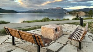 Two wooden benches facing a lake with mountains in the background. - Lake Dillon Condominium with Beautiful Lake & Mountain Views. Sleeps 4. (Dillon)