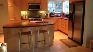 A modern kitchen with wooden cabinets, a stainless steel refrigerator, a microwave, and a gas stove. - Charming Creekside Country Home (Sutter Creek)