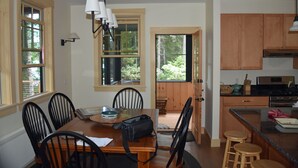A dining area with a wooden table, chairs, and a kitchen with wooden cabinets and a countertop.