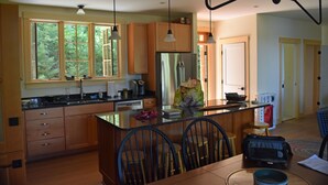 A modern kitchen with wooden cabinets, a central island, and pendant lighting.