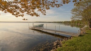A calm lake with a wooden dock extending into the water, surrounded by rocks and grass.