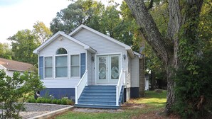 Une petite maison de plain-pied avec un porche à l’avant et un petit jardin.