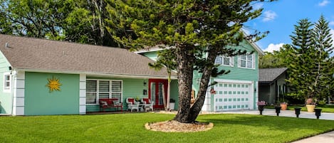 A two-story house with a garage, a red door, and a lawn.