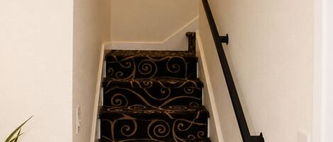 A staircase with a patterned carpet and black handrail.