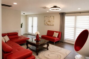 A living room with a red sofa set, a coffee table with a vase, and a modern chair. - Hudson Waterfront Home in Beacon Woods Community W/ Access to Club Amenities (Bayonet Point)