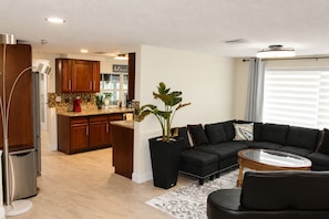 A modern living room with a dark sofa, a glass coffee table, and a potted plant. - Hudson Waterfront Home in Beacon Woods Community W/ Access to Club Amenities (Bayonet Point)