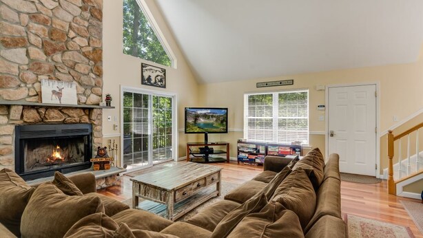 A spacious living room with a stone fireplace, a large television, and a comfortable seating area. - MASTHOPE-BIG BEAR-LACKAWAXEN-LUXURY 4 Bedroom-Game Room (Lackawaxen)