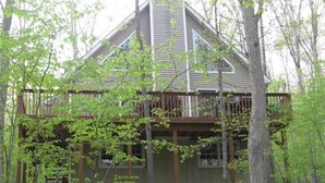 A cabin with a wooden deck, surrounded by trees. - MASTHOPE-BIG BEAR-LACKAWAXEN-LUXURY 4 Bedroom-Game Room (Lackawaxen)