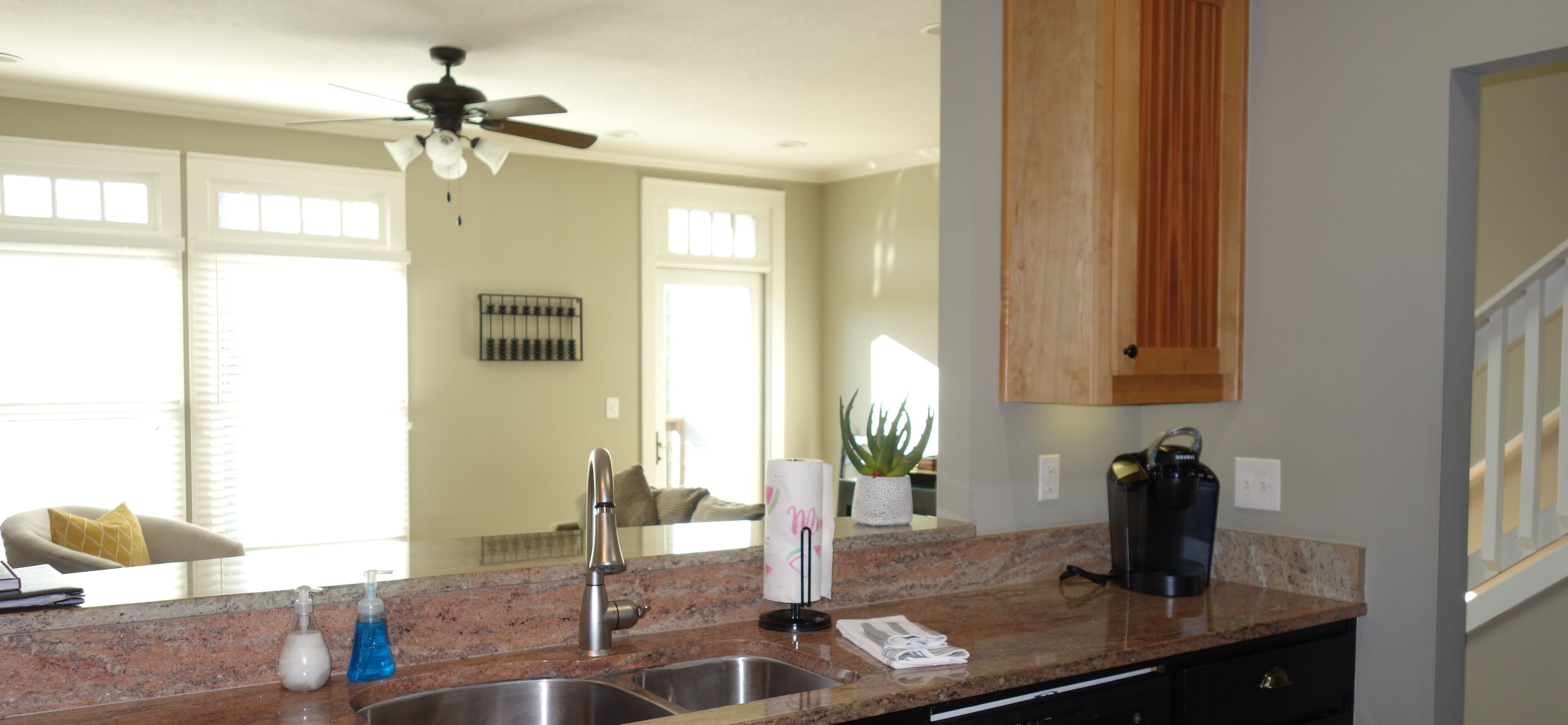 A modern kitchen with granite countertops, stainless steel appliances, and a ceiling fan.