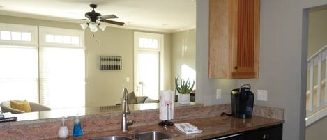 A modern kitchen with granite countertops, stainless steel appliances, and a ceiling fan.
