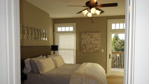 A bedroom with a bed, a ceiling fan, a painting, and a window with blinds.