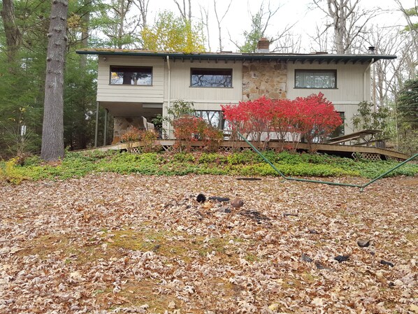 A two-story house with a stone facade, a wooden deck, and a garden with red foliage. - Beckman Peninsula Spectacular Location! (Swanton)