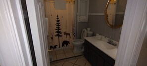 A bathroom with a shower curtain featuring animal silhouettes, a toilet, a sink with a mirror, and a towel rack. - Beckman Peninsula Spectacular Location! (Swanton)
