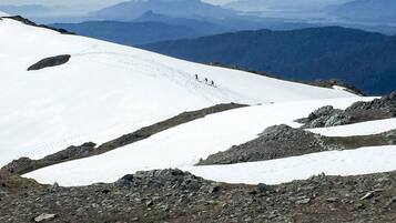 A snow-covered mountain slope with a clear path and distant mountains.