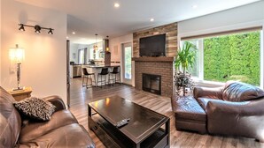 A modern living room with a fireplace, leather sofas, a coffee table, and a TV.